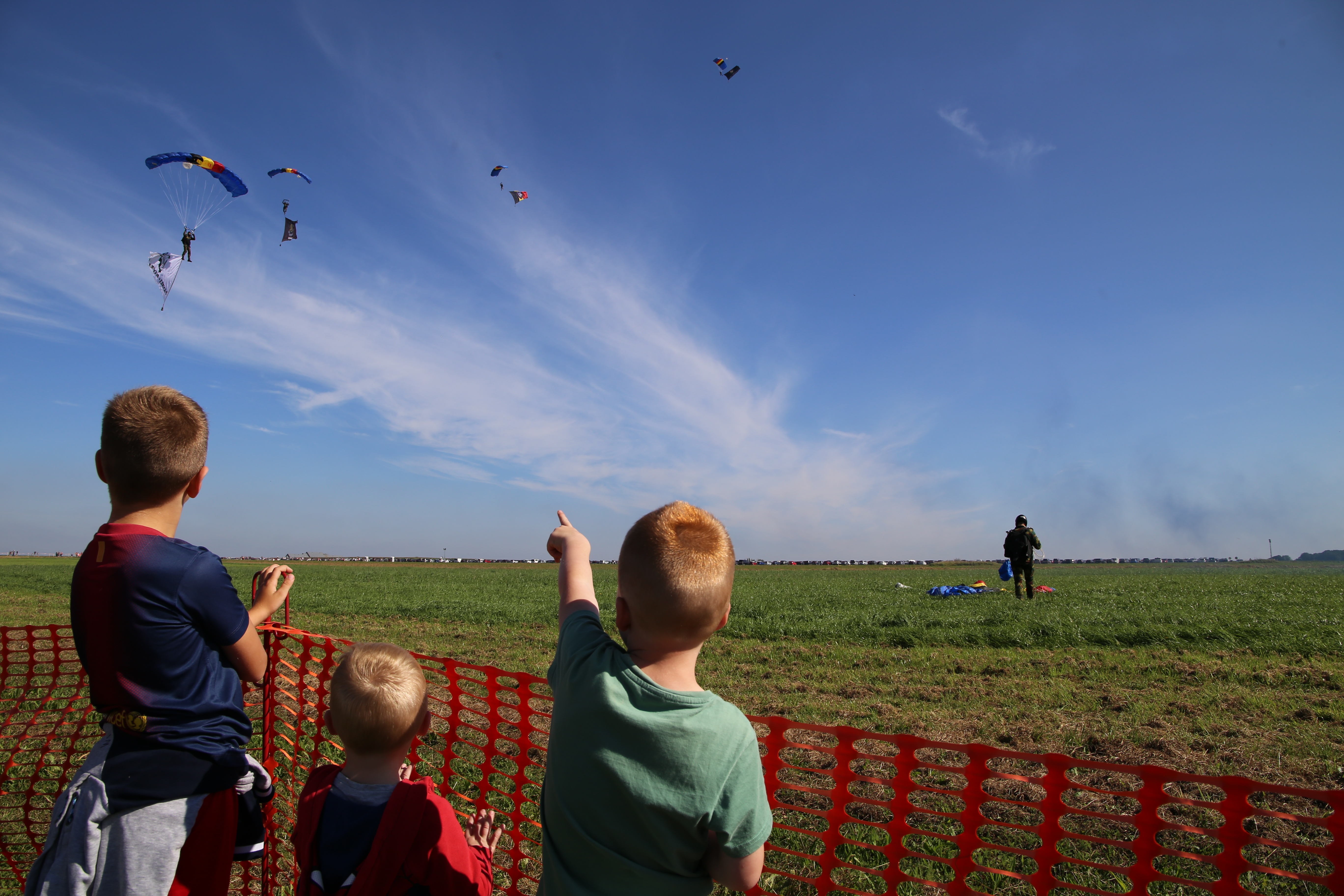 a photograph of children watching paratroopers in the sky
