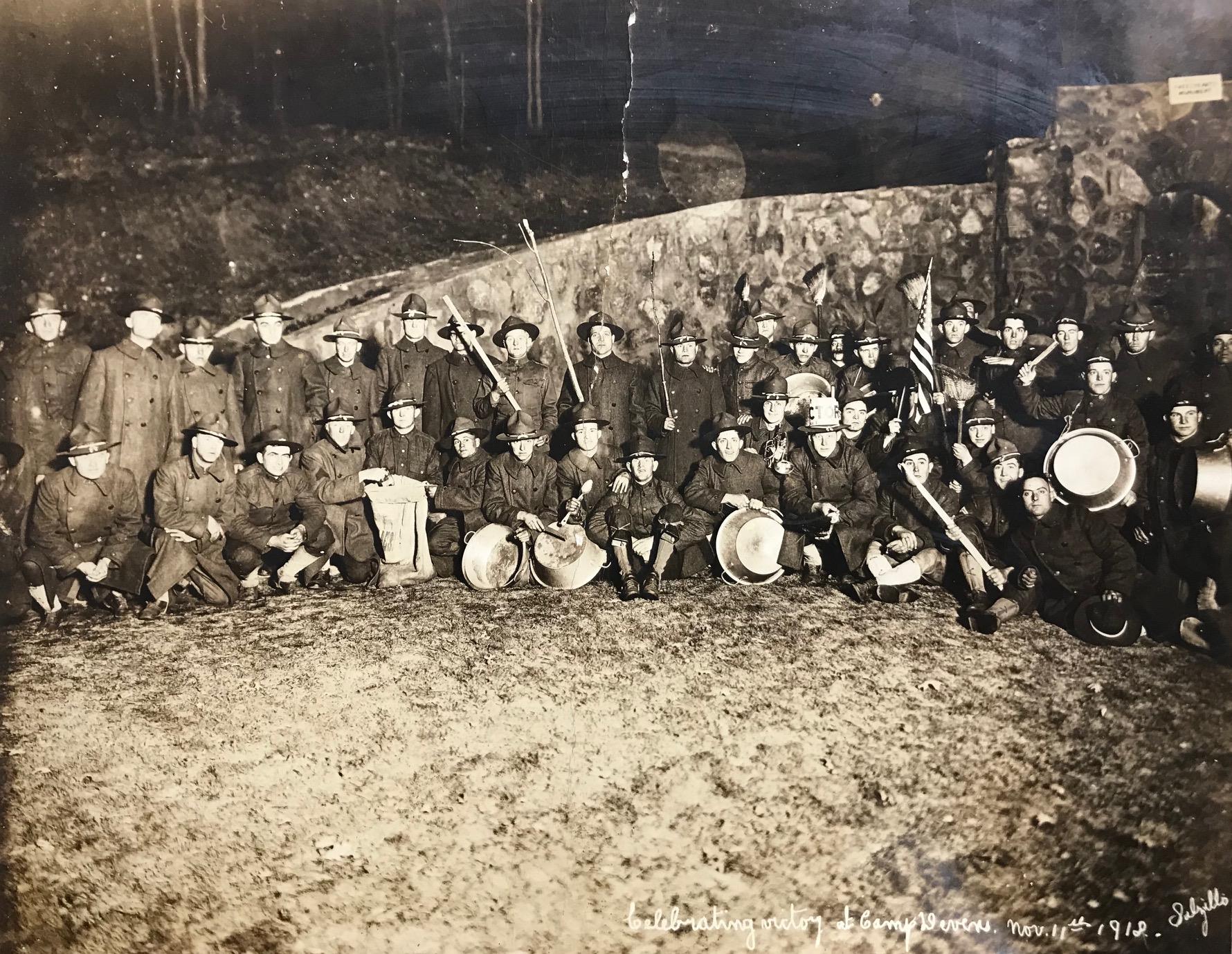 This photograph was taken at Camp Devens on November 11, 1918 in front of the Sweetheart Memorial on Jackson Road. In celebration-and to make lots of noise-the revelers carried "all kinds [of implements] from broom handles to dishpans, and lots of them, too."