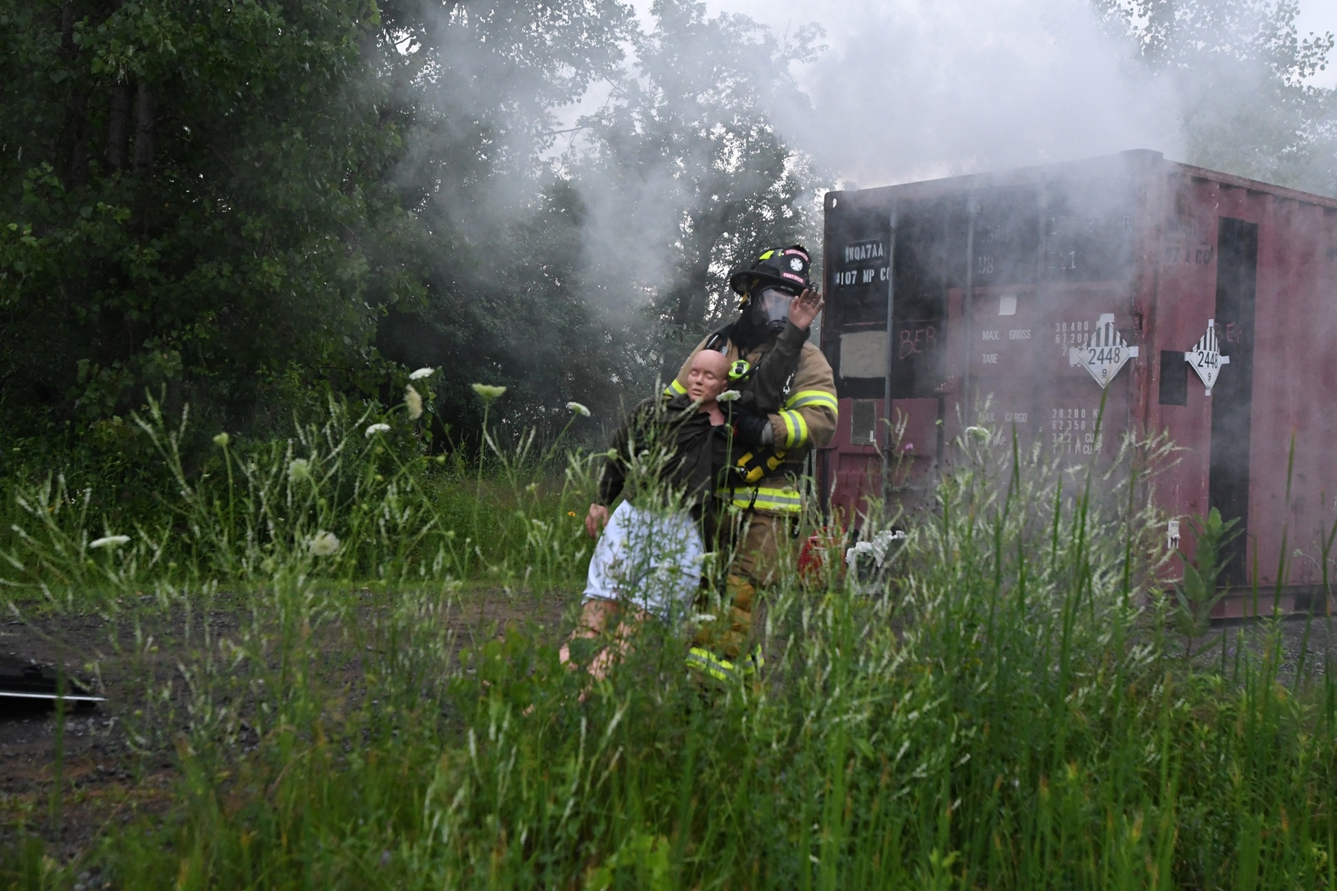 Firefighter pulls casualty away from derailed train car during exercise.