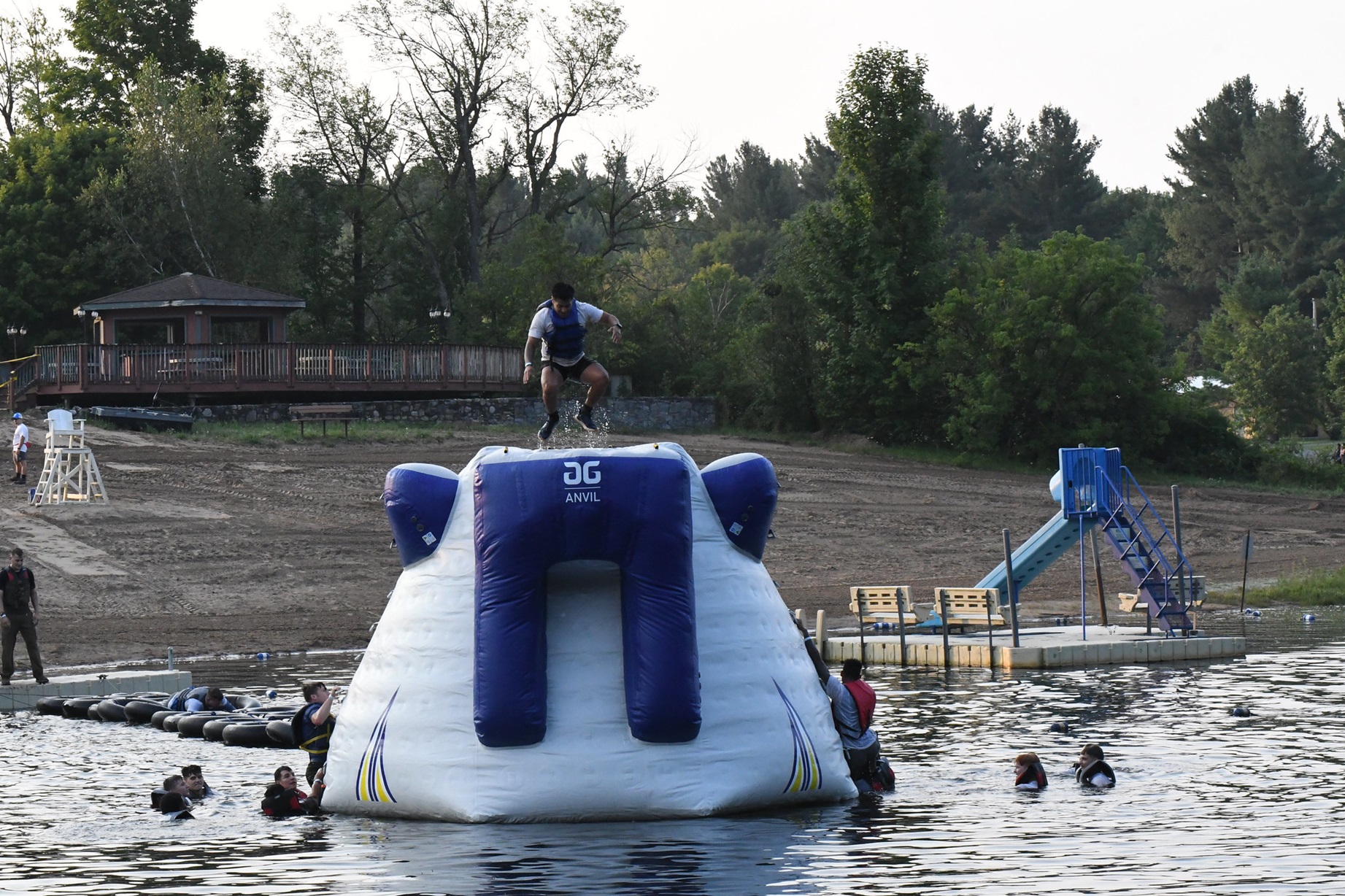 Man climbs to the top of an inflatable mountain in Remington Pond during the 2024 Mountain Mudder.