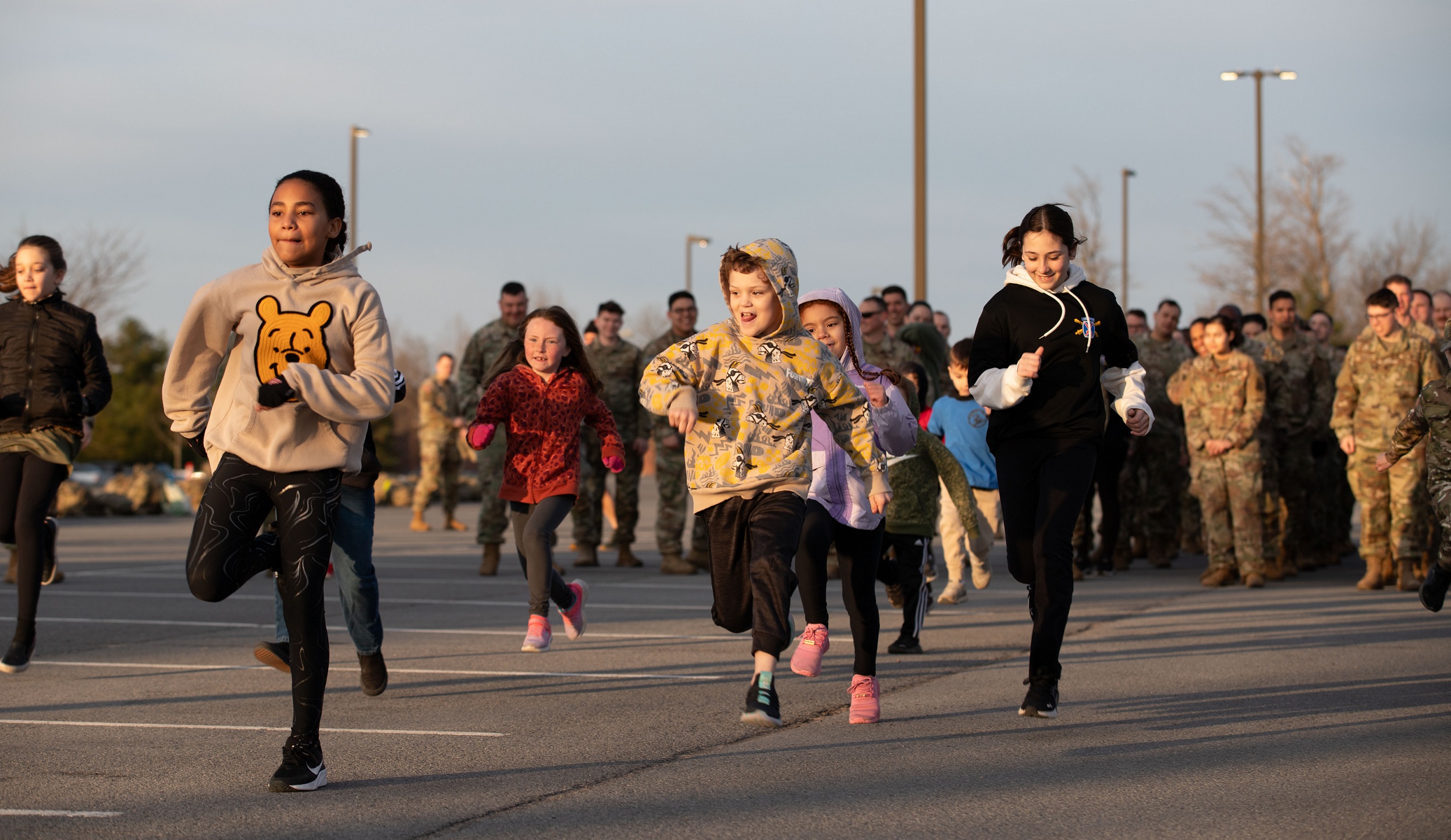 Children run ahead of Soldiers in formation