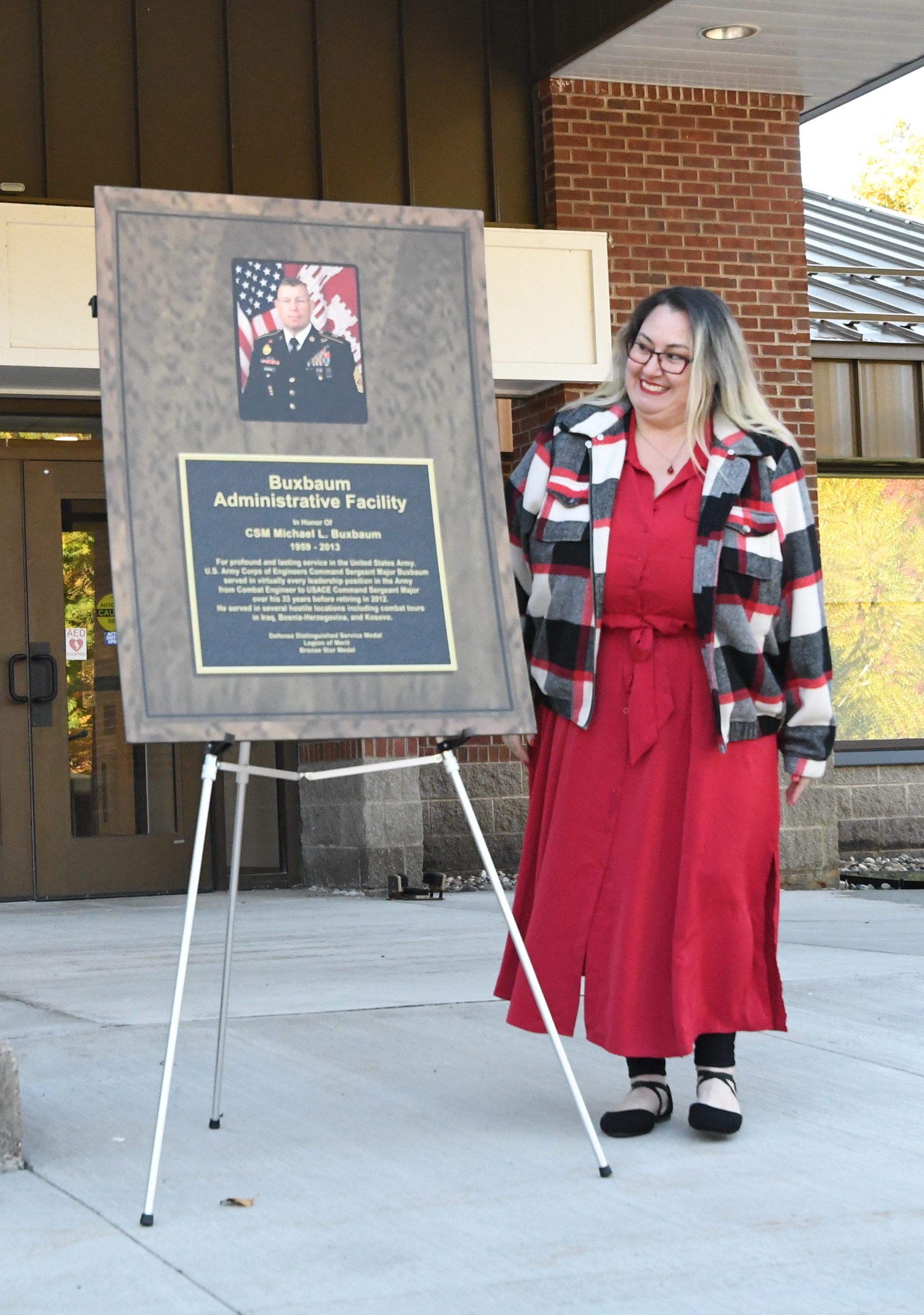 Woman unveils memorial plaque at Buxbaum Administrative Facility memorialization.