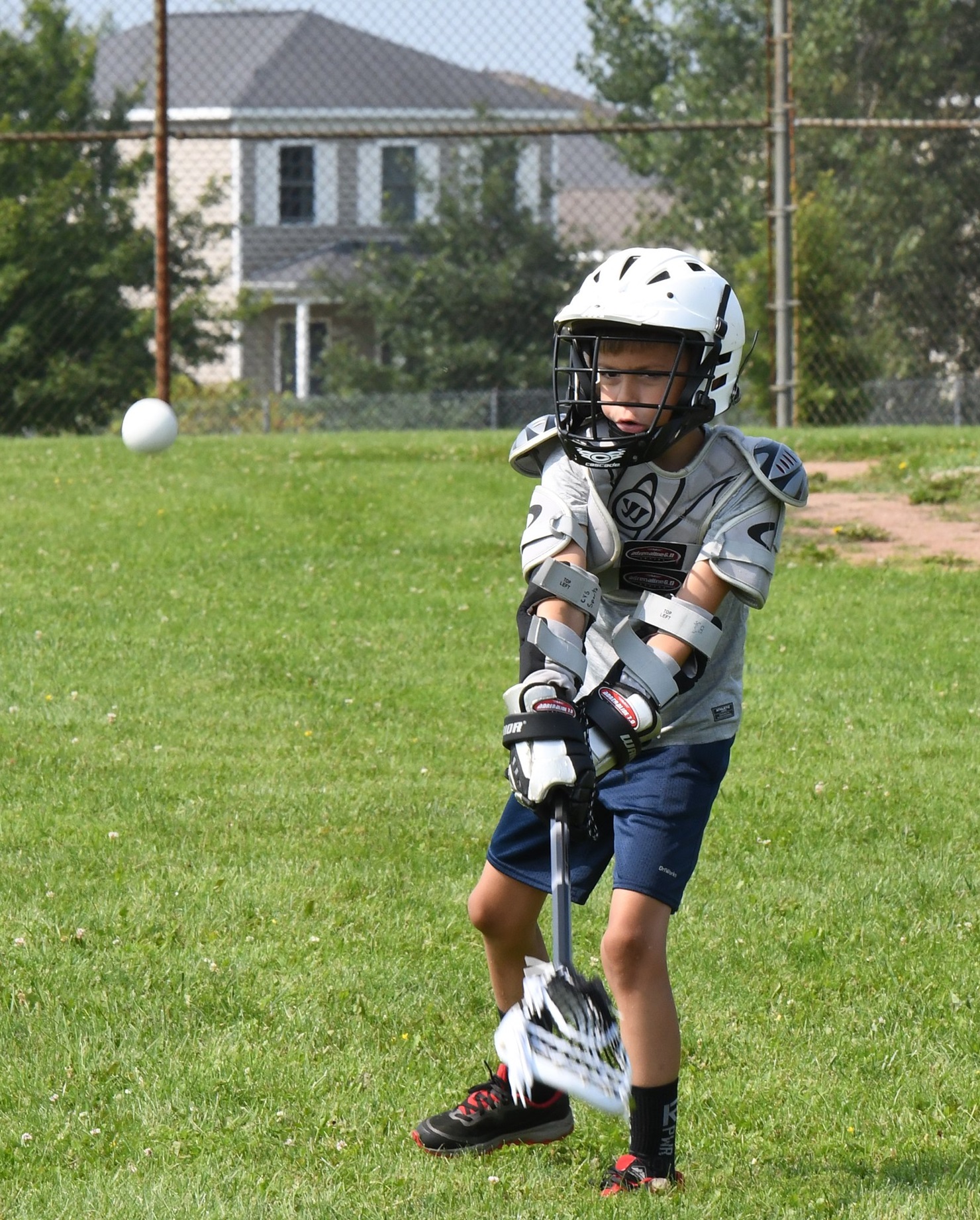 Boy hits ball with lacrosse racket at CYS Summer Camp.