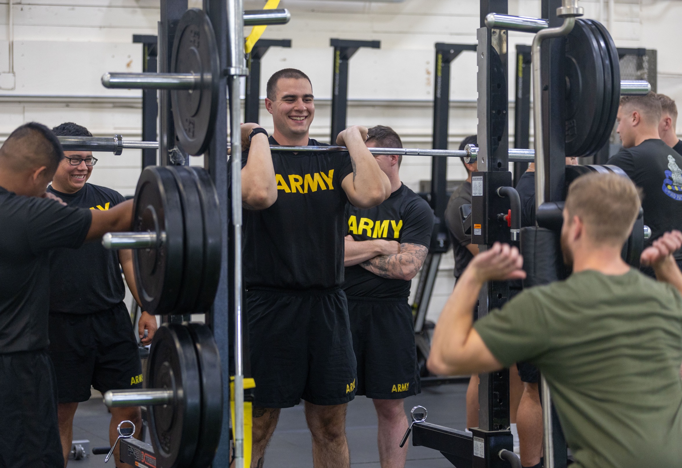 Soldier at weight set learns about proper form from civilian coach.