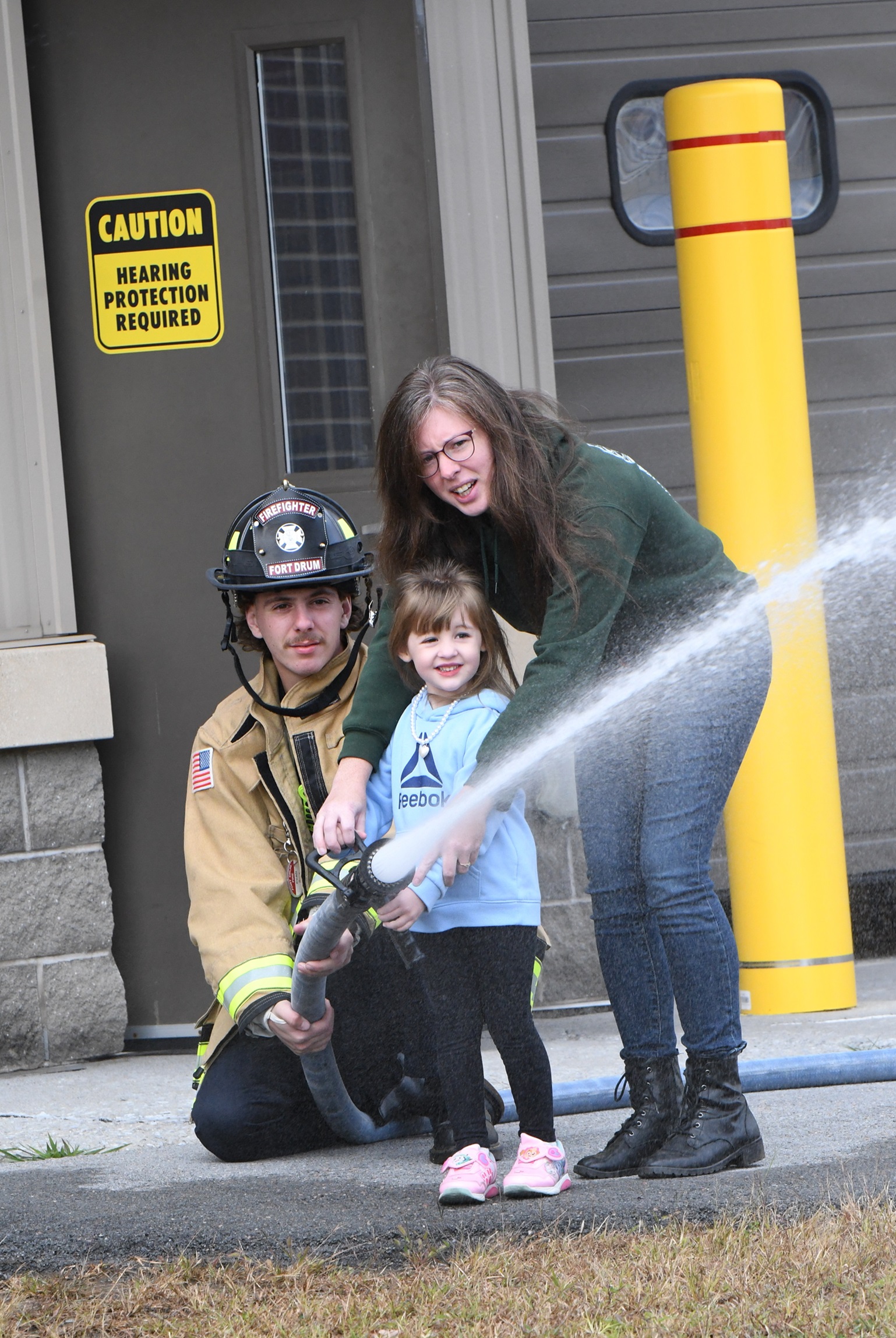 Girl tries out firefighter hose during Fort Drum Fire Department Open House.