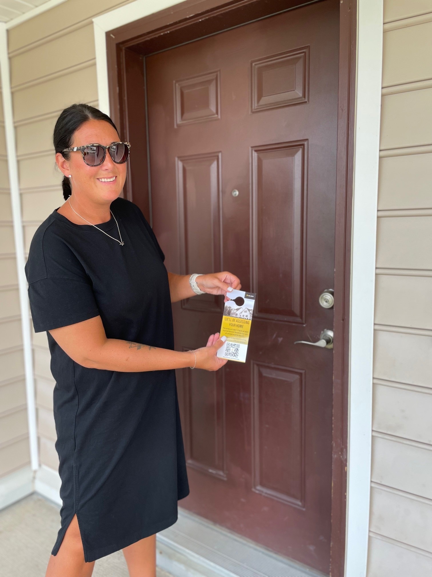 Woman places hanger on door with information on upcoming housing inspections.