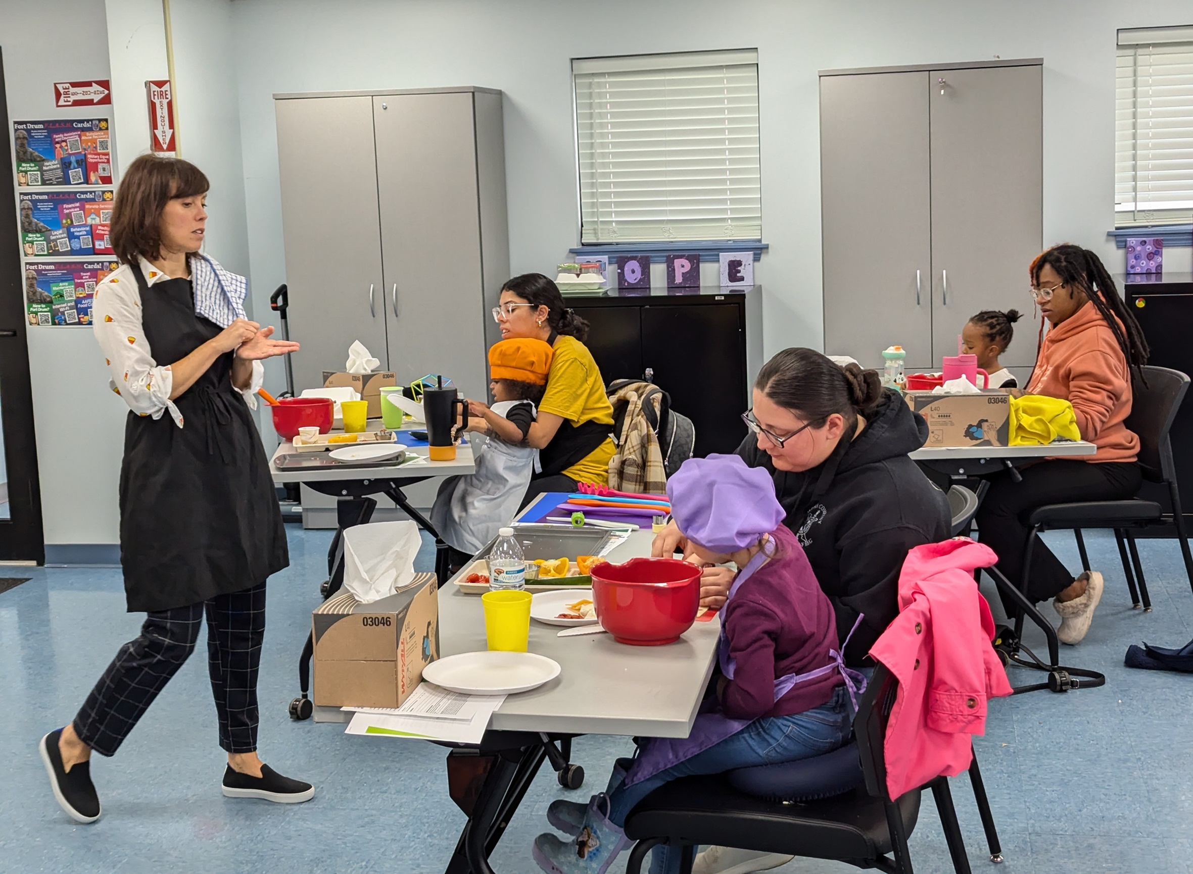 Instructor addresses mothers and kids as they cut vegetables during Sensory Eating Adventures class.
