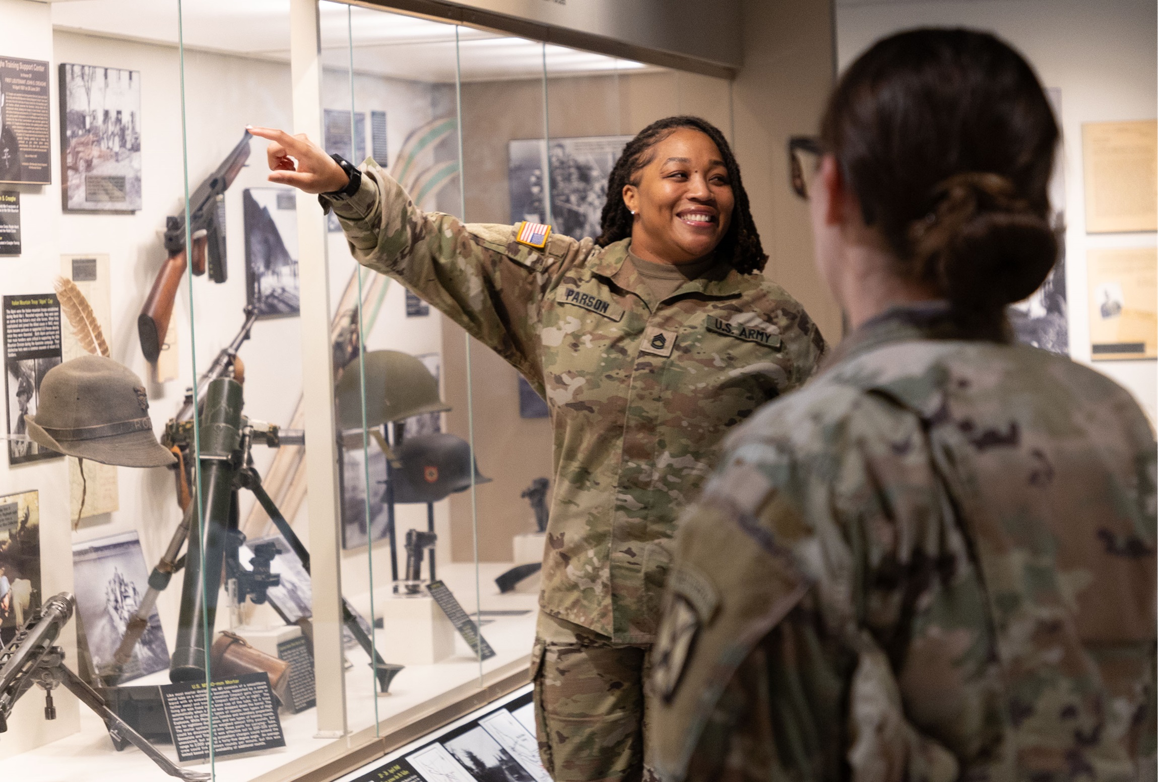 Female Soldier points to photo on display at the 10th Mountain Division and Fort Drum Museum.