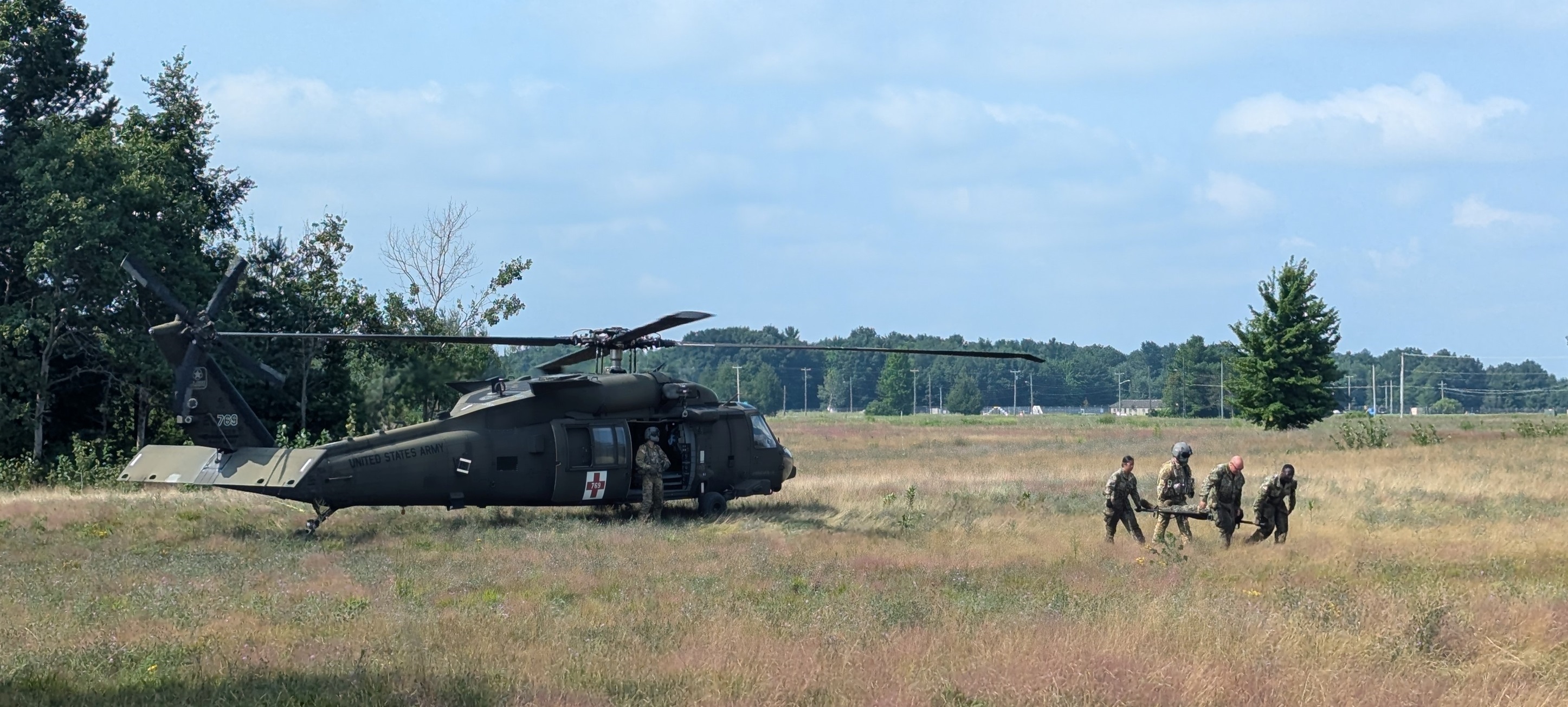 Navy Reservists transport a casualty away from a helicopter in a field during training at Fort Drum.
