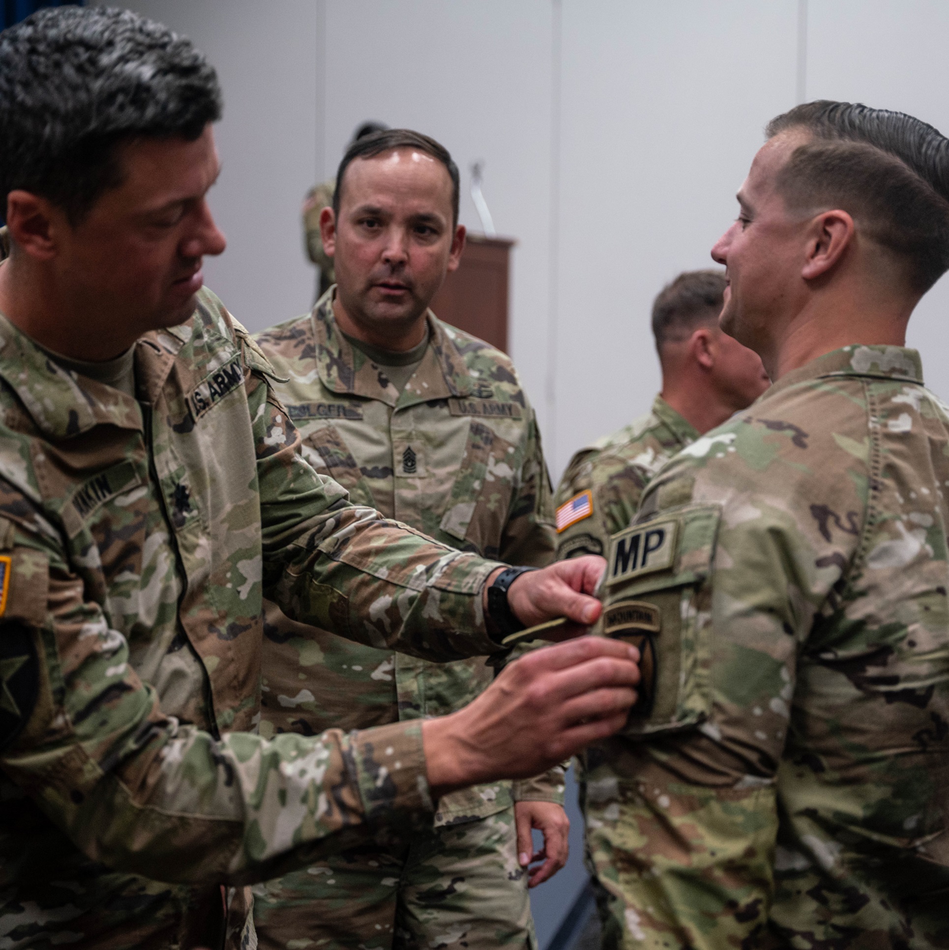 Commander places 10th Mountain Division patch on Soldier's sleeve.