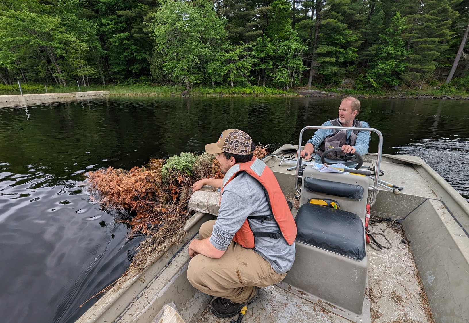 Natural Resources staff travel by boat looking for a spot to lower a bundles of trees.