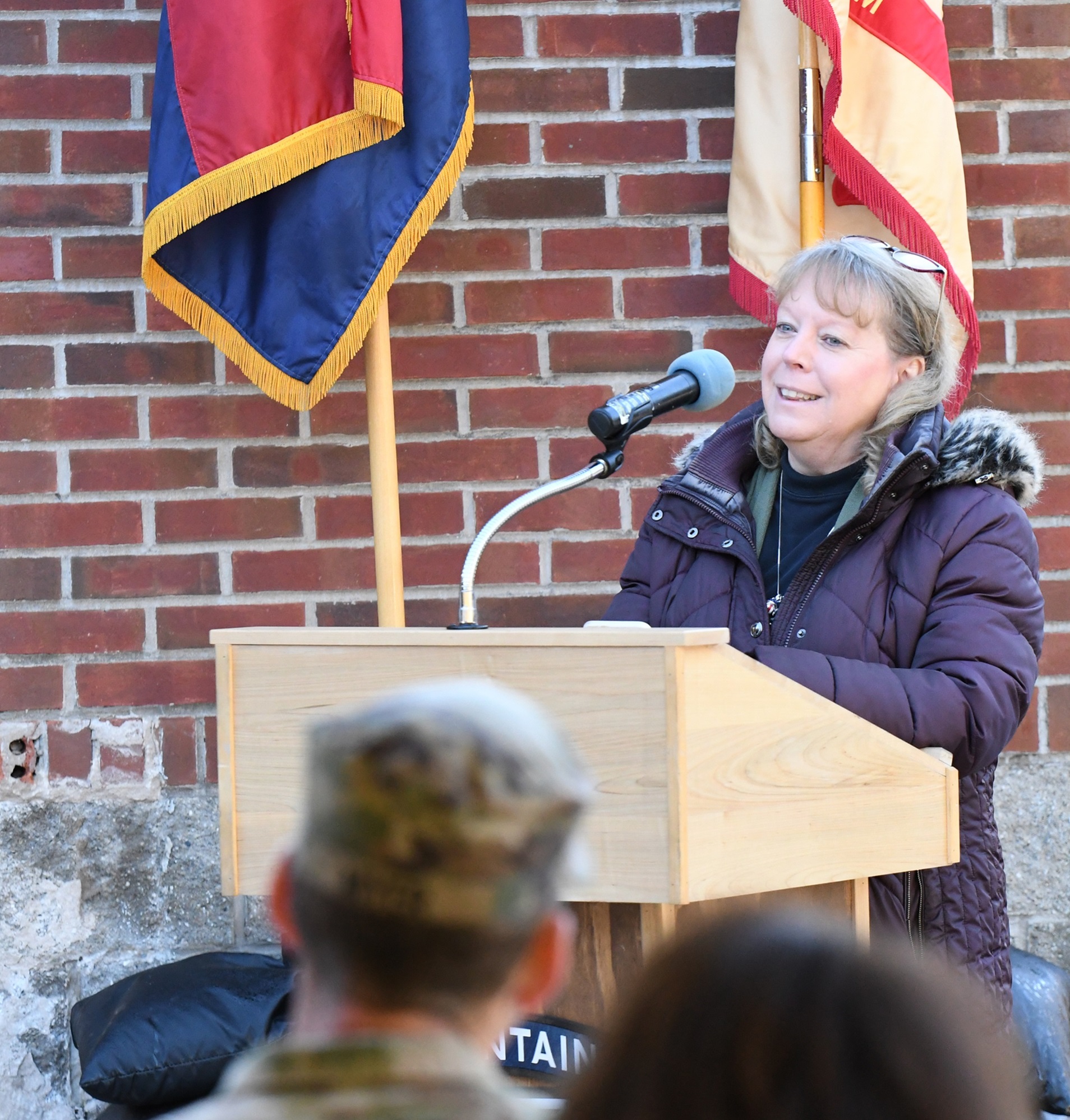 Woman speaks at podiium during Buxbaum Administrative Facility memorialization.