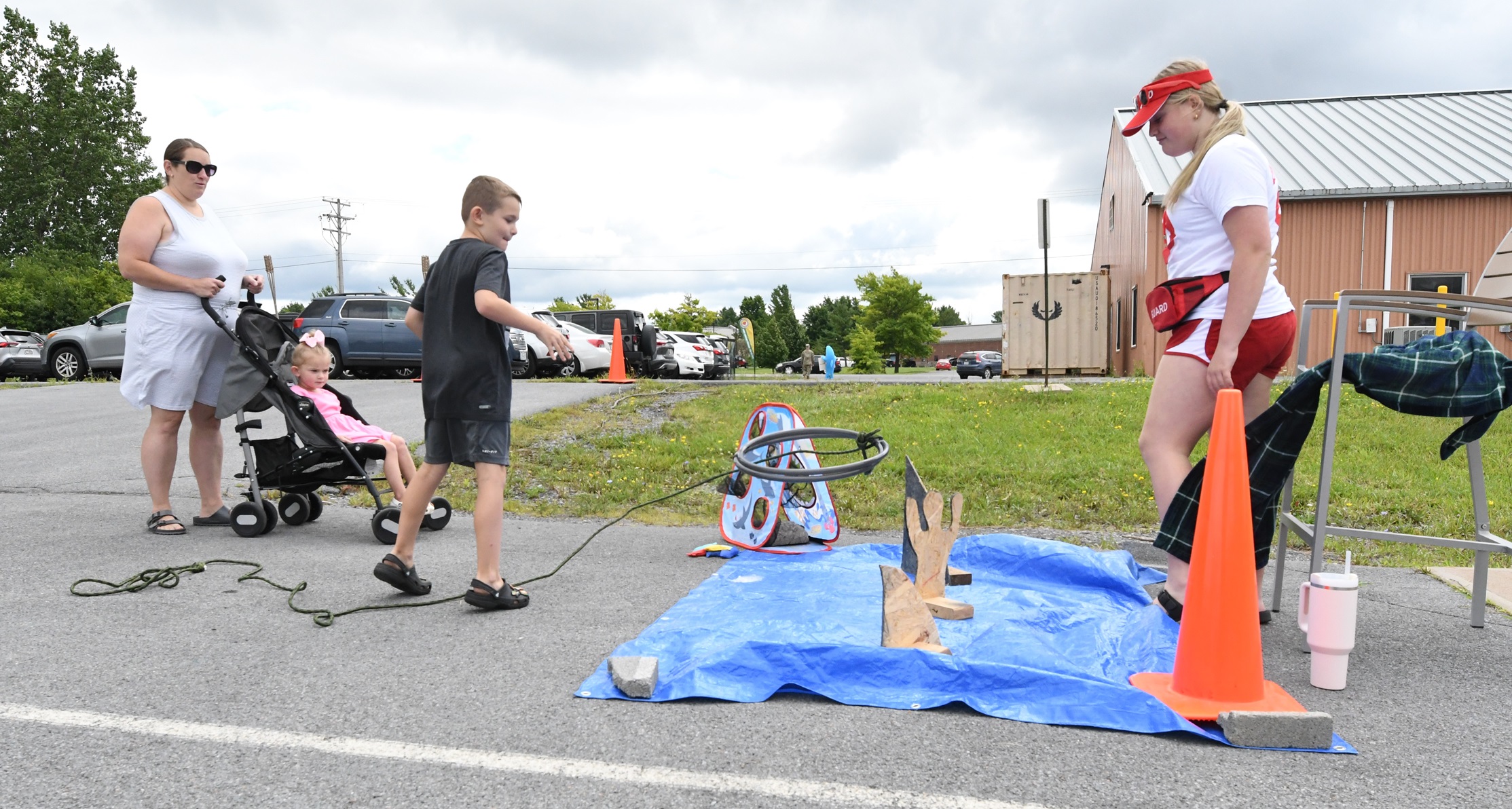 A youth throws a hoop over a cutout of a person in the Save the Swimmer activity.