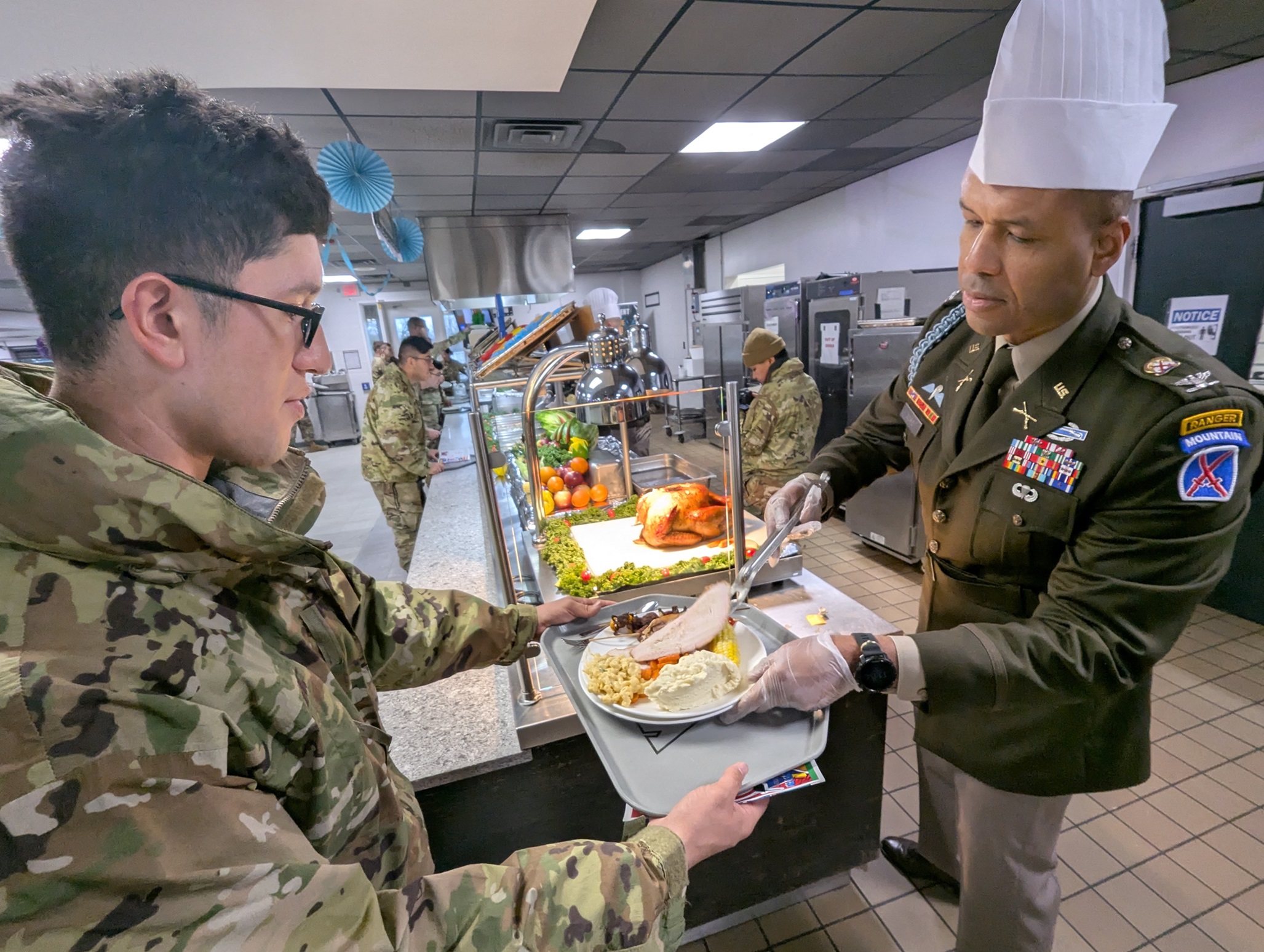 Officer serves turkey to a Soldier during Thanksgiving 2024 meal in the dining facility.