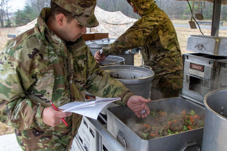 Soldiers work in field kitchen.