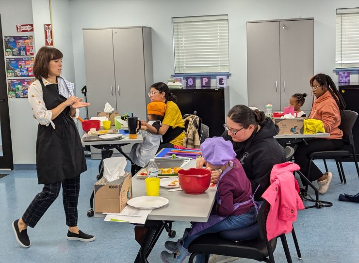 Instructor addresses mothers and kids as they cut vegetables during Sensory Eating Adventures class.