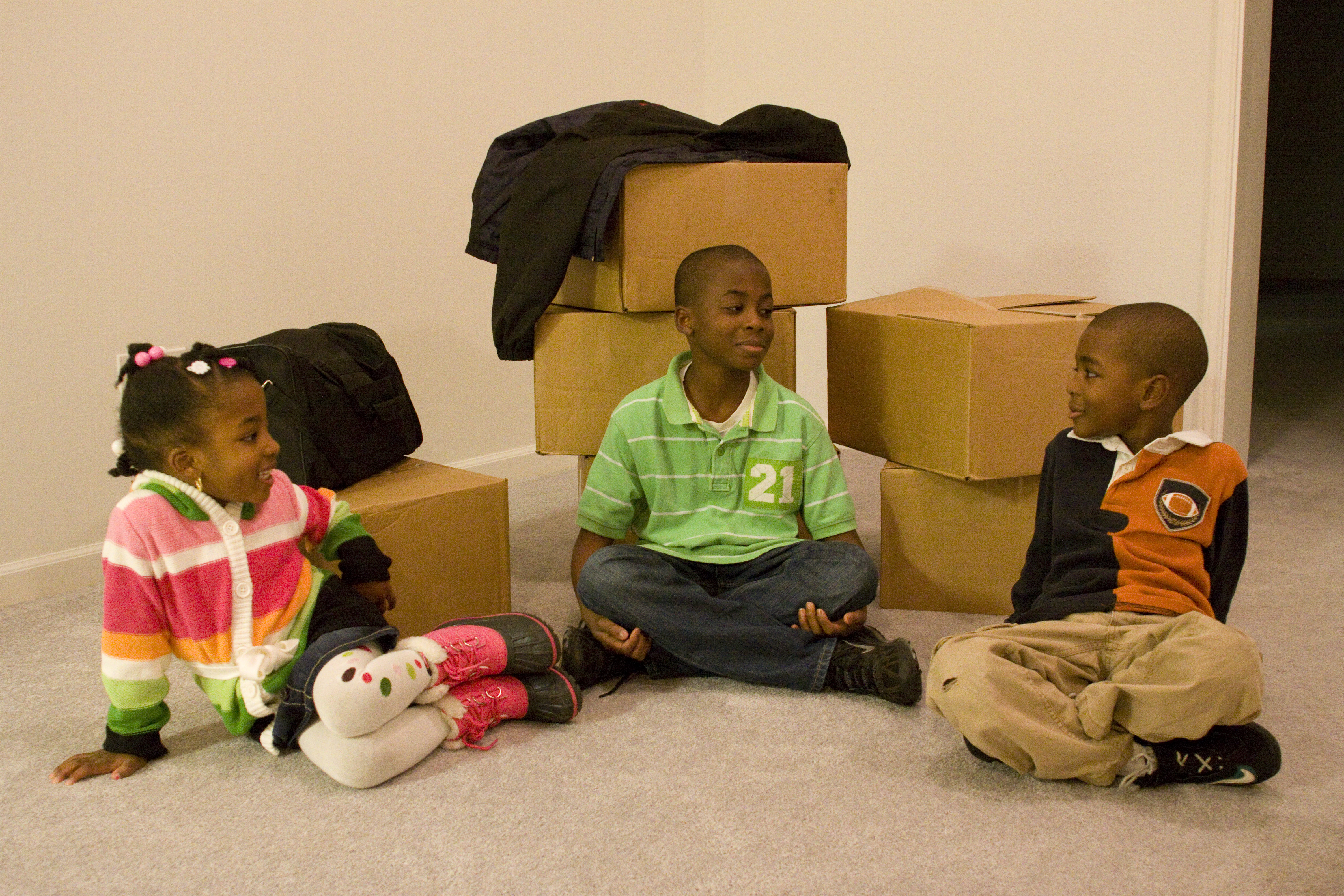Military dependents sitting with moving boxes behind them