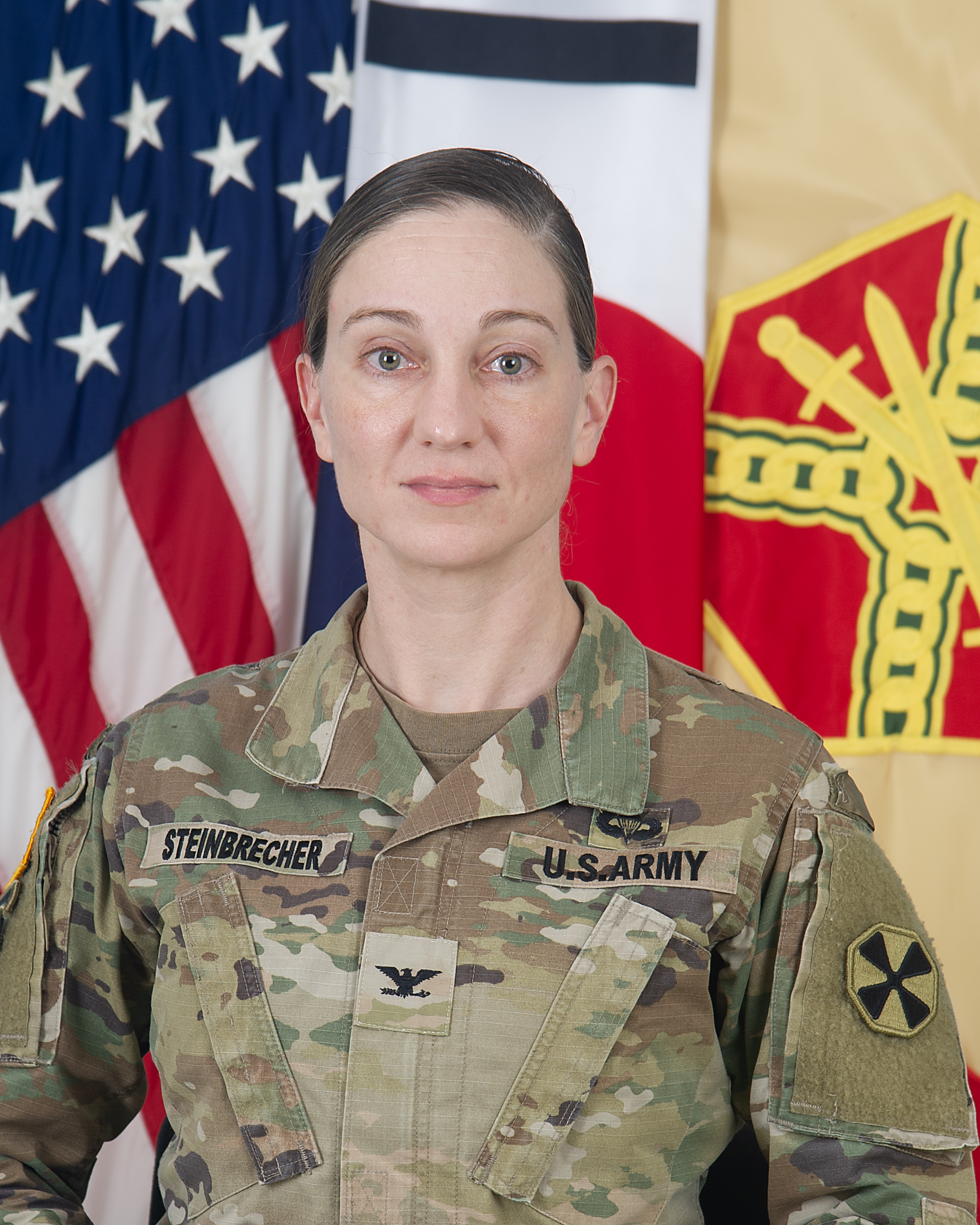 Colonel Ryan K. Workman, USAG Humphreys Garrison Commander, in front of the flags of the United States of America, Republic of Korea and Installation Management Command.
