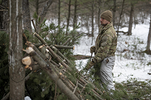 Photo: A Cold-Weather Operations Course class 22-04 student builds an improvised shelter Feb. 16 at a training area on South Post at Fort McCoy.