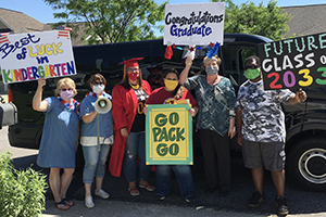 Photo: CYS staff members hold graduation signs in front of a van.