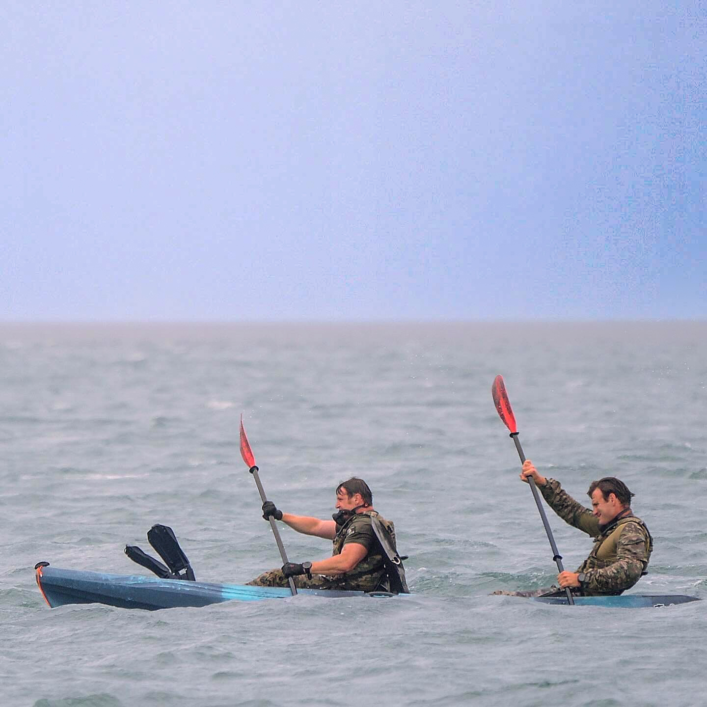 This photo captures two Soldiers kayaking through open water, each paddling with focused determination 
