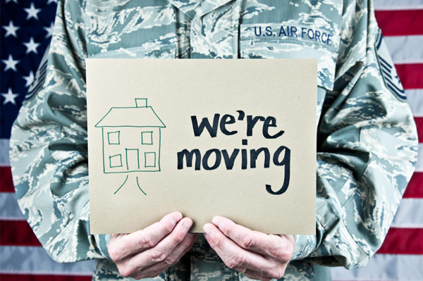 Photo of an Airman holding a sign that says "We're Moving!"